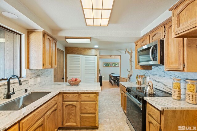 kitchen featuring backsplash, light stone countertops, light tile patterned floors, sink, and stainless steel appliances