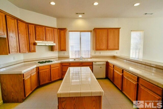 kitchen featuring tile countertops, a center island, white appliances, and light tile patterned floors