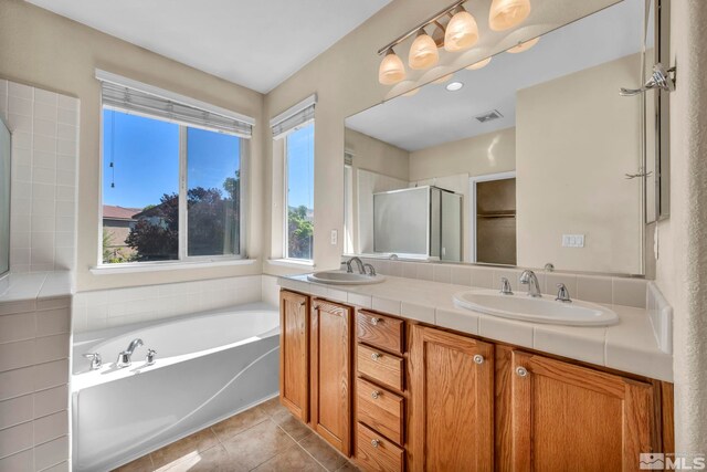 bathroom featuring shower with separate bathtub, double sink vanity, tile patterned floors, and a healthy amount of sunlight