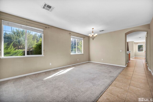 empty room with an inviting chandelier and light tile patterned floors