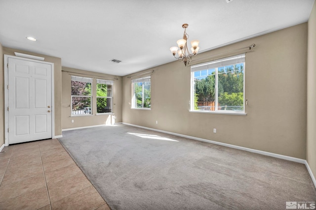 empty room featuring carpet floors, baseboards, a notable chandelier, and tile patterned floors