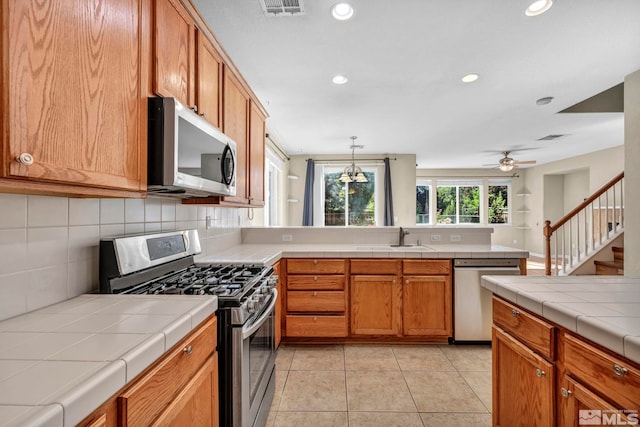 kitchen with light tile patterned floors, visible vents, appliances with stainless steel finishes, a peninsula, and a sink