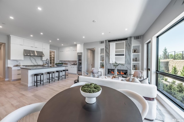 dining room with sink, built in features, light hardwood / wood-style floors, and a premium fireplace