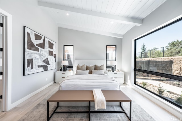 bedroom with multiple windows, vaulted ceiling with beams, and light hardwood / wood-style floors