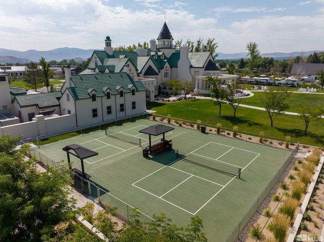 view of tennis court featuring a mountain view and a lawn