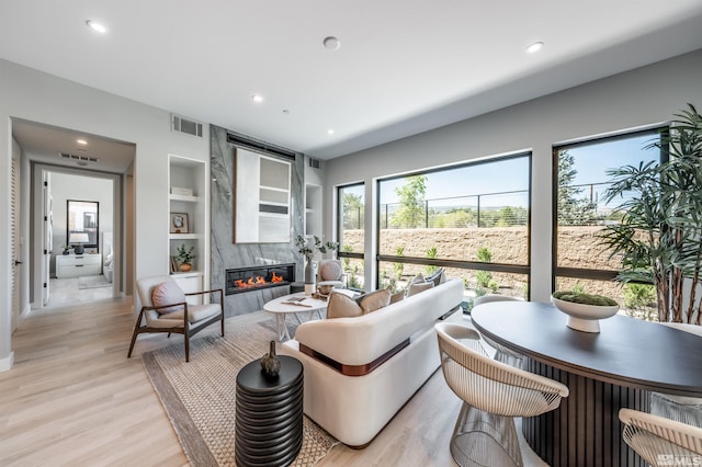 living room featuring a fireplace, light hardwood / wood-style flooring, and built in shelves