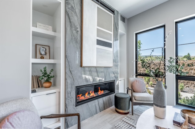 sitting room featuring built in features, a fireplace, and wood-type flooring