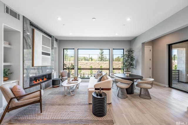 living room featuring light wood-type flooring and a large fireplace