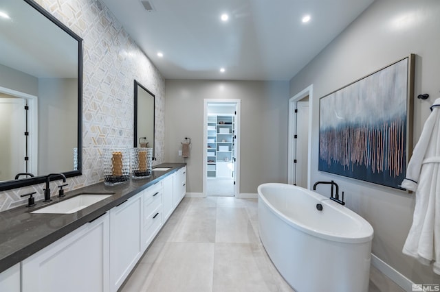 bathroom with double vanity, a soaking tub, a sink, and baseboards