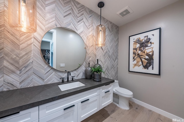 bathroom with baseboards, visible vents, toilet, wood finished floors, and vanity