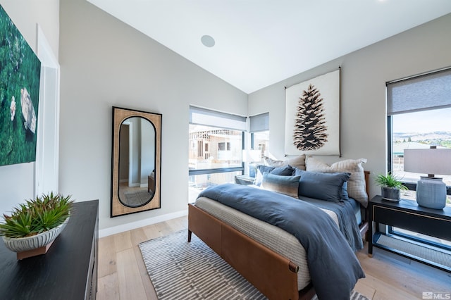 bedroom featuring high vaulted ceiling, light wood-style flooring, and baseboards