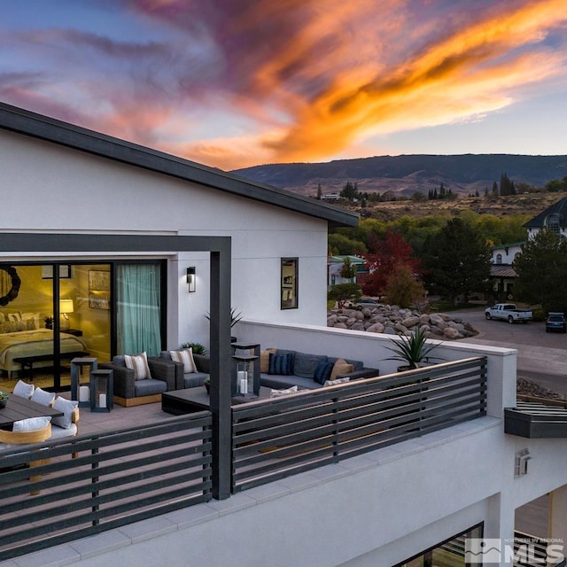 patio terrace at dusk featuring a mountain view, an outdoor living space, and a balcony