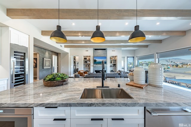 kitchen with hanging light fixtures, white cabinetry, stainless steel appliances, and light stone counters