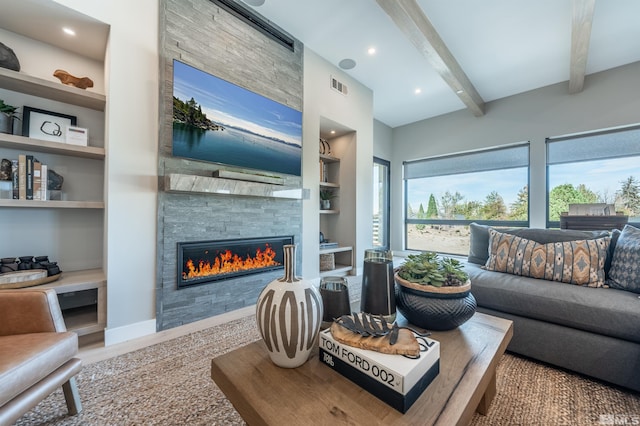 living room featuring built in features, beam ceiling, a fireplace, visible vents, and baseboards