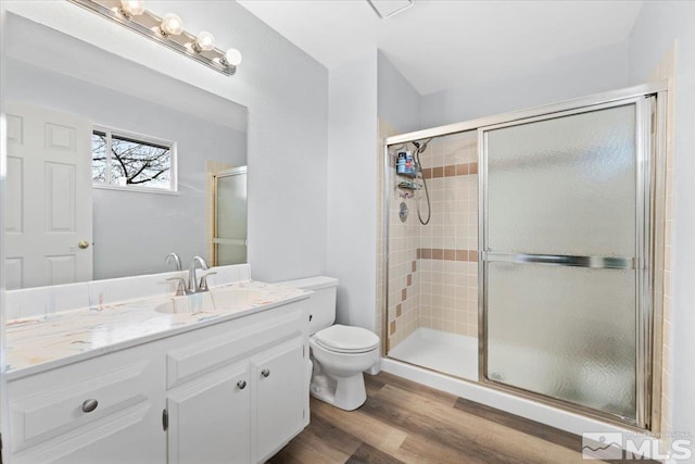 bathroom with vanity, a shower stall, toilet, and wood finished floors