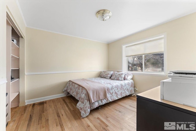 bedroom featuring crown molding, light wood finished floors, and baseboards