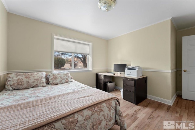 bedroom featuring baseboards, crown molding, and light wood finished floors