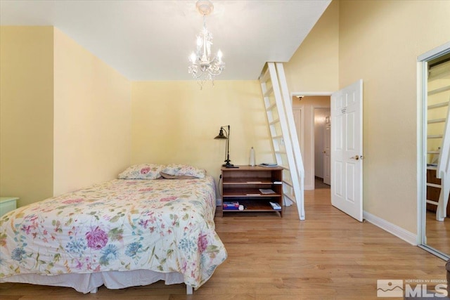 bedroom with baseboards, a chandelier, and wood finished floors