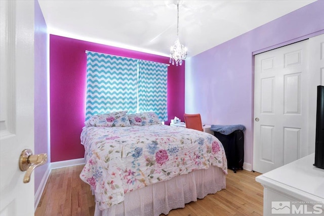 bedroom featuring baseboards, wood finished floors, and a notable chandelier