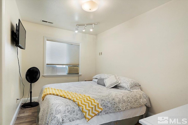 bedroom featuring wood finished floors, visible vents, and baseboards