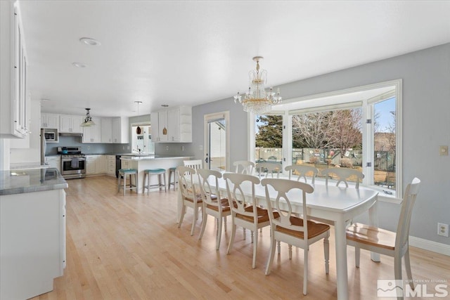 dining room featuring a chandelier, light wood finished floors, and baseboards