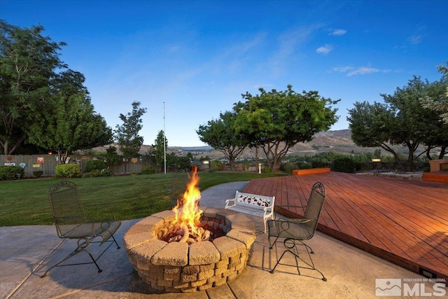 view of patio featuring a fire pit, a deck with mountain view, and fence