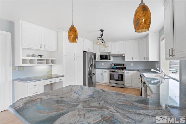 kitchen with under cabinet range hood, a sink, white cabinetry, light wood-style floors, and appliances with stainless steel finishes