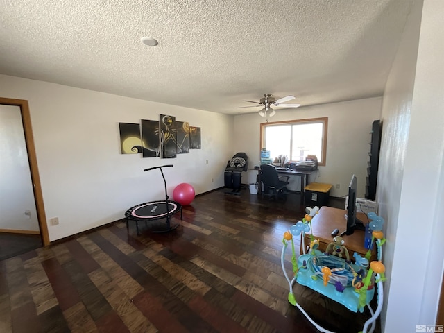 recreation room with baseboards, a textured ceiling, wood finished floors, and a ceiling fan
