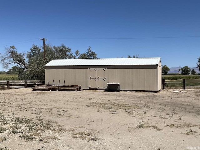 view of outbuilding featuring a rural view, an outdoor structure, and fence