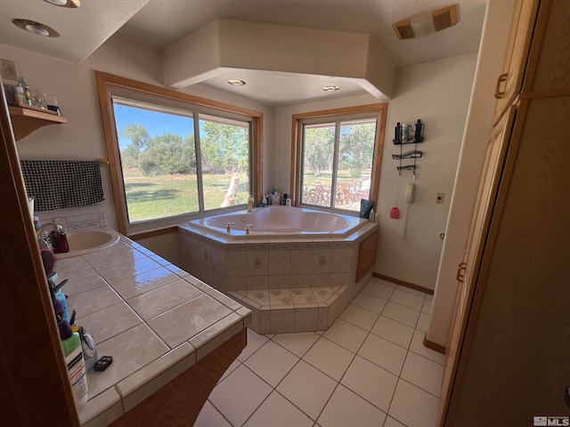 bathroom featuring sink, a relaxing tiled tub, and tile patterned flooring