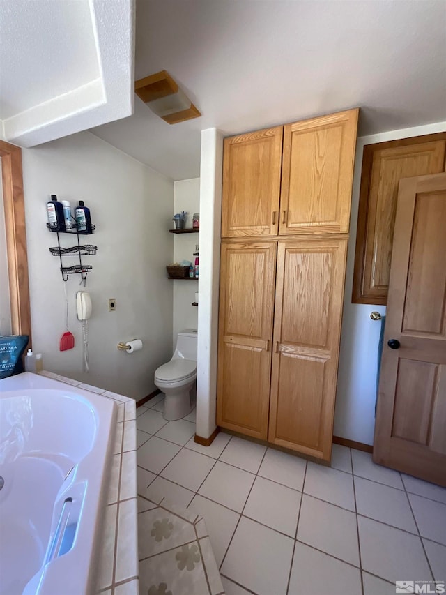 bathroom with tile patterned flooring, a bathtub, and toilet