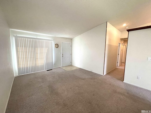 carpeted spare room with a textured ceiling and lofted ceiling