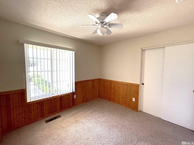 interior space featuring a textured ceiling, a closet, ceiling fan, and light carpet