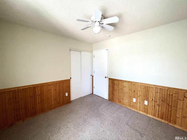 carpeted spare room with a textured ceiling and ceiling fan