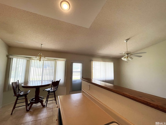 tiled dining room with a textured ceiling and ceiling fan with notable chandelier