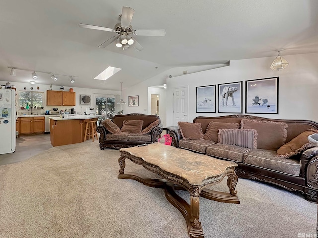 carpeted living room with lofted ceiling with skylight and ceiling fan