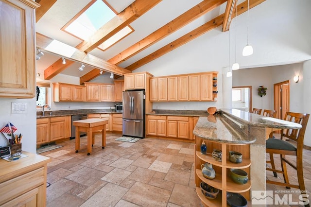 kitchen with light brown cabinets, a skylight, appliances with stainless steel finishes, beamed ceiling, and light tile patterned flooring