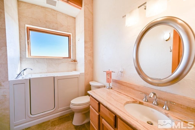 bathroom featuring tile patterned flooring, toilet, a bathtub, and vanity