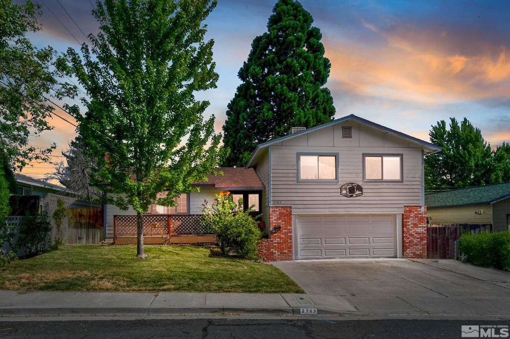 split level home featuring a garage and a yard