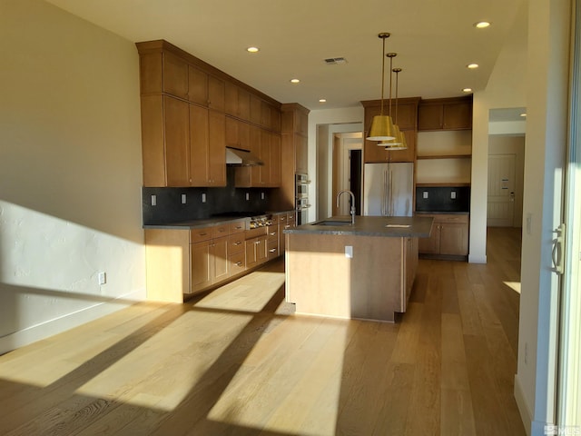 kitchen featuring pendant lighting, sink, light hardwood / wood-style flooring, an island with sink, and stainless steel appliances