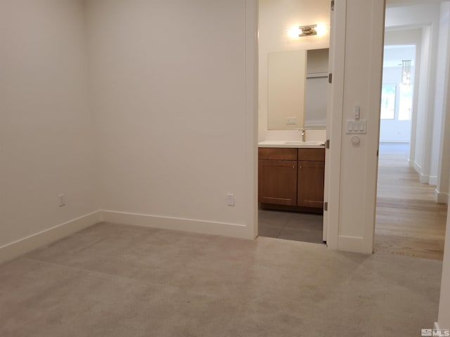 interior space with connected bathroom, sink, and light colored carpet