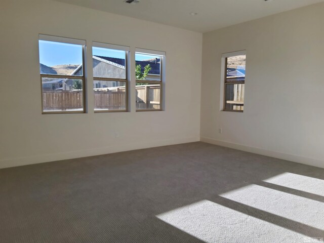 empty room with a mountain view, plenty of natural light, and dark colored carpet