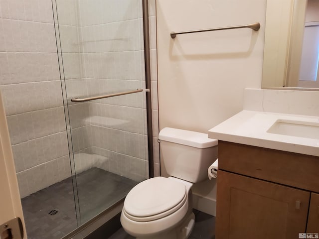 bathroom with vanity, toilet, and a shower with door