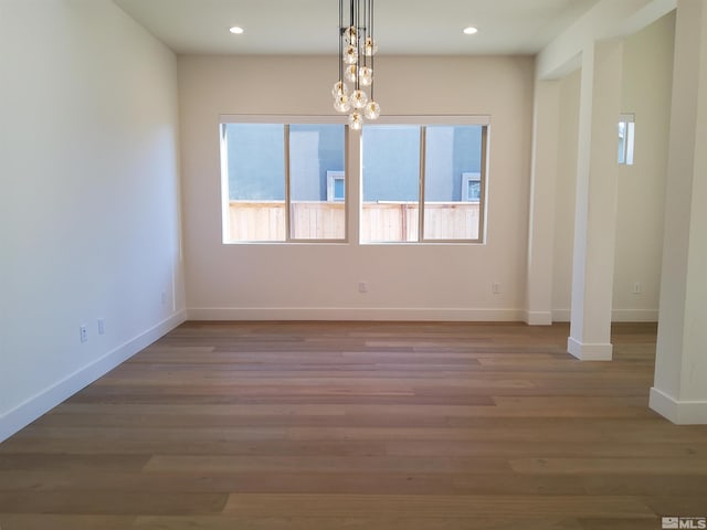 spare room featuring a chandelier and light hardwood / wood-style flooring