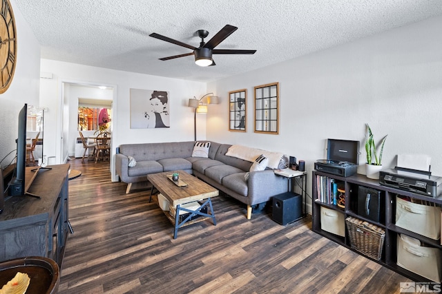 living room with a textured ceiling, ceiling fan, and dark wood-type flooring