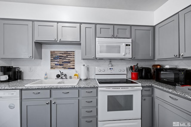 kitchen featuring sink, decorative backsplash, white appliances, and gray cabinetry