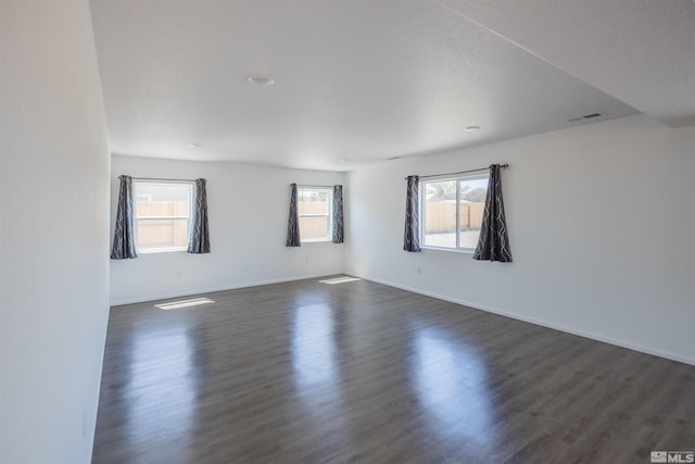 empty room with plenty of natural light and dark wood-type flooring