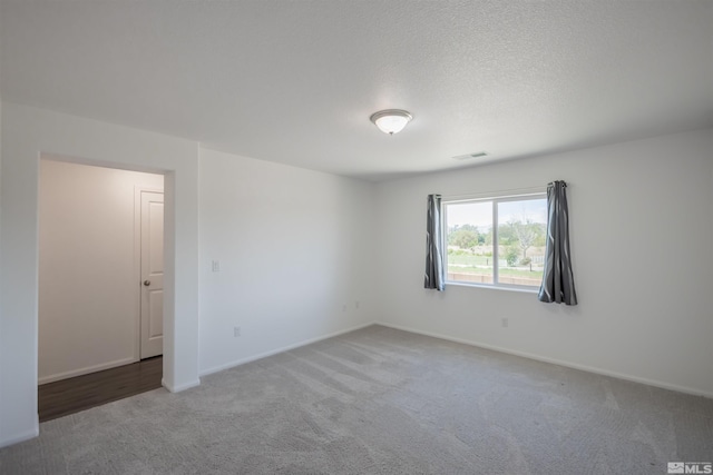 unfurnished room with a textured ceiling and carpet floors