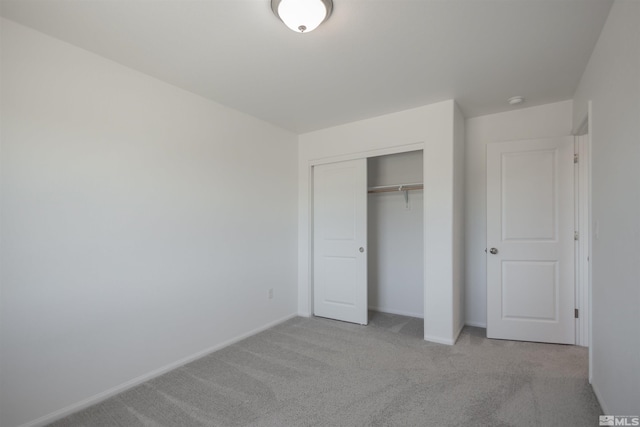 unfurnished bedroom with light colored carpet and a closet