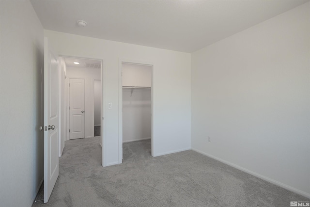 unfurnished bedroom with a walk in closet, light colored carpet, and a closet